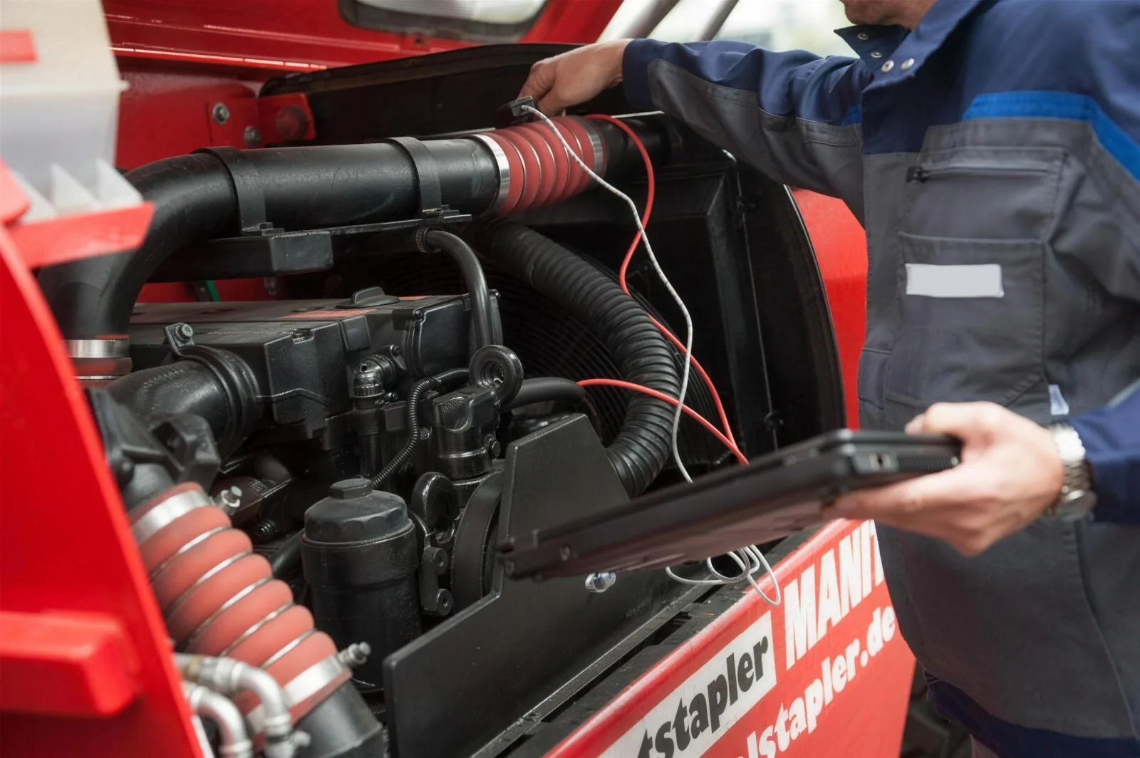 Servicetechniker von HERBST bei der Fehlerdiagnose am Motor eines Manitou-Teleskopladers